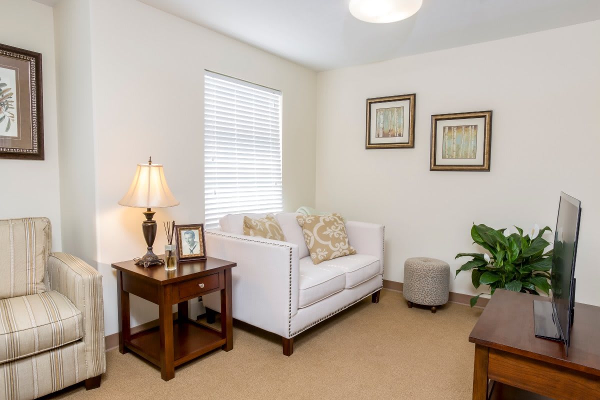 A cozy living room with a white sofa, side table, lamp, and decorative artwork.