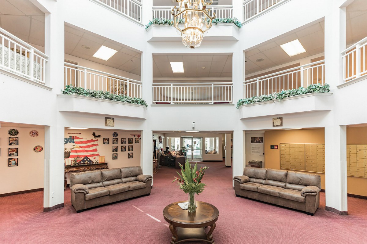 A spacious lobby with a chandelier, surrounded by balconies and adorned with elegant furnishings.