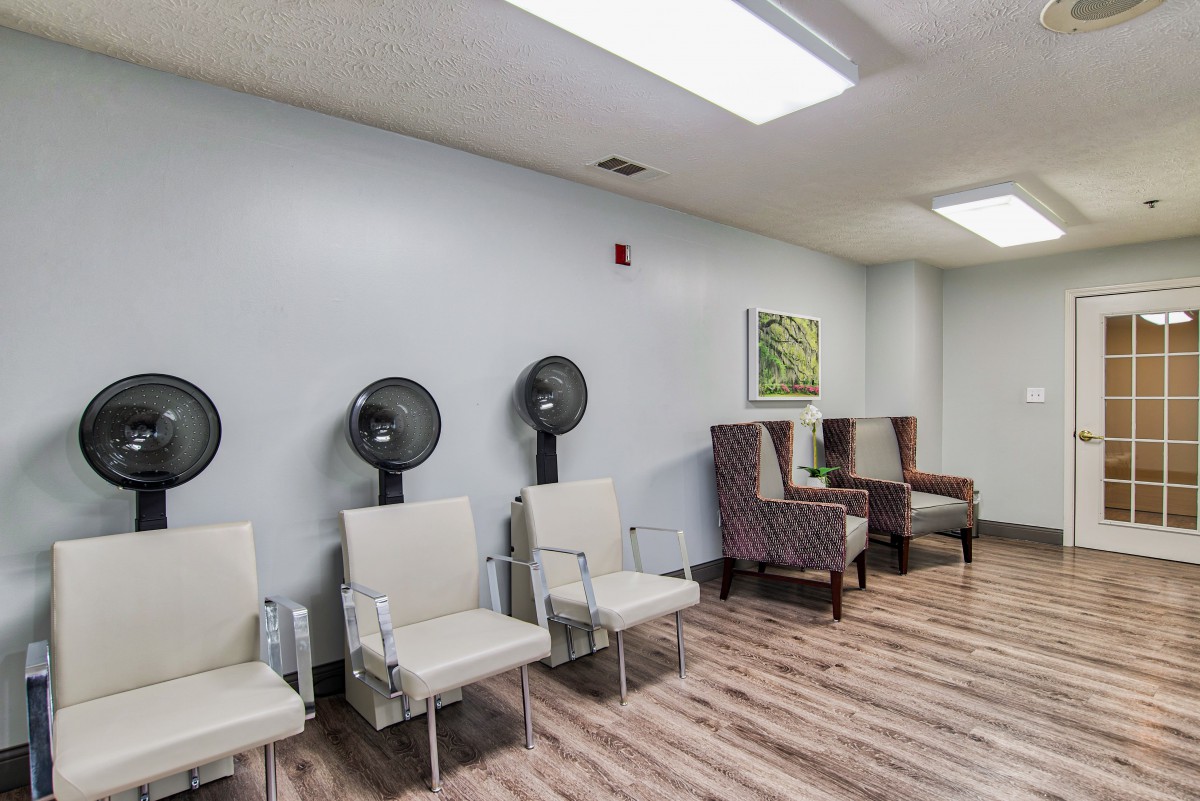 A modern salon waiting area with chairs and wall-mounted hair dryers.