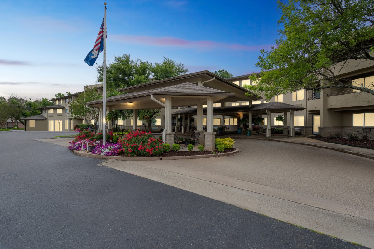A building's entrance with a flag and landscaped surroundings.