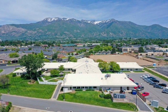 An aerial view of a building with a mountainous backdrop in a suburban setting.