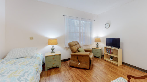 A cozy and well-lit living room featuring a recliner, bedside tables with lamps, and a television.