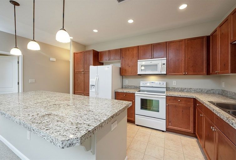 A modern kitchen with granite countertops and wood cabinets.