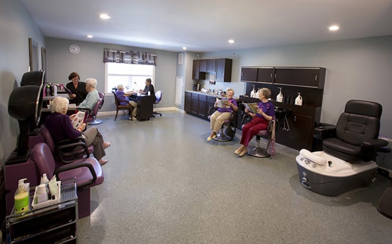 A group of seniors sit in a waiting area of a hair salon.