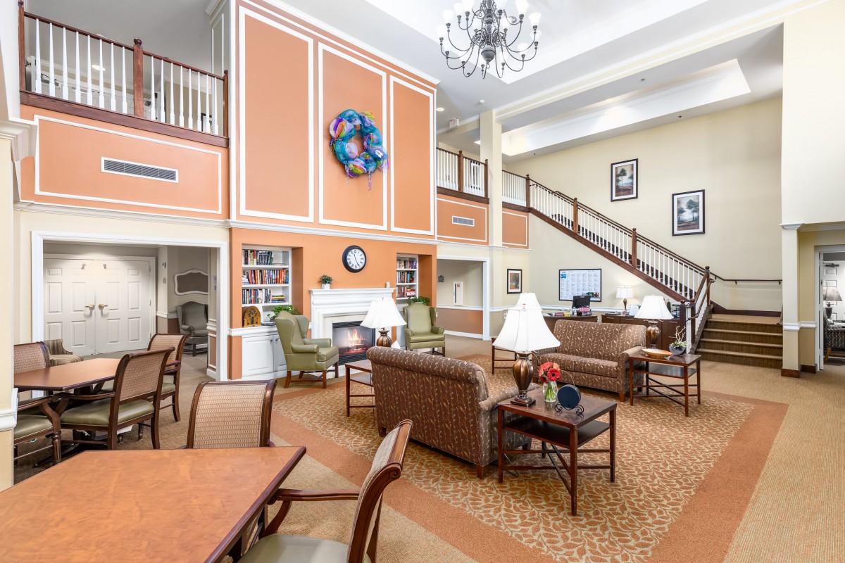 A spacious and cozy lounge area with comfortable seating, a large chandelier, and an elegant staircase.