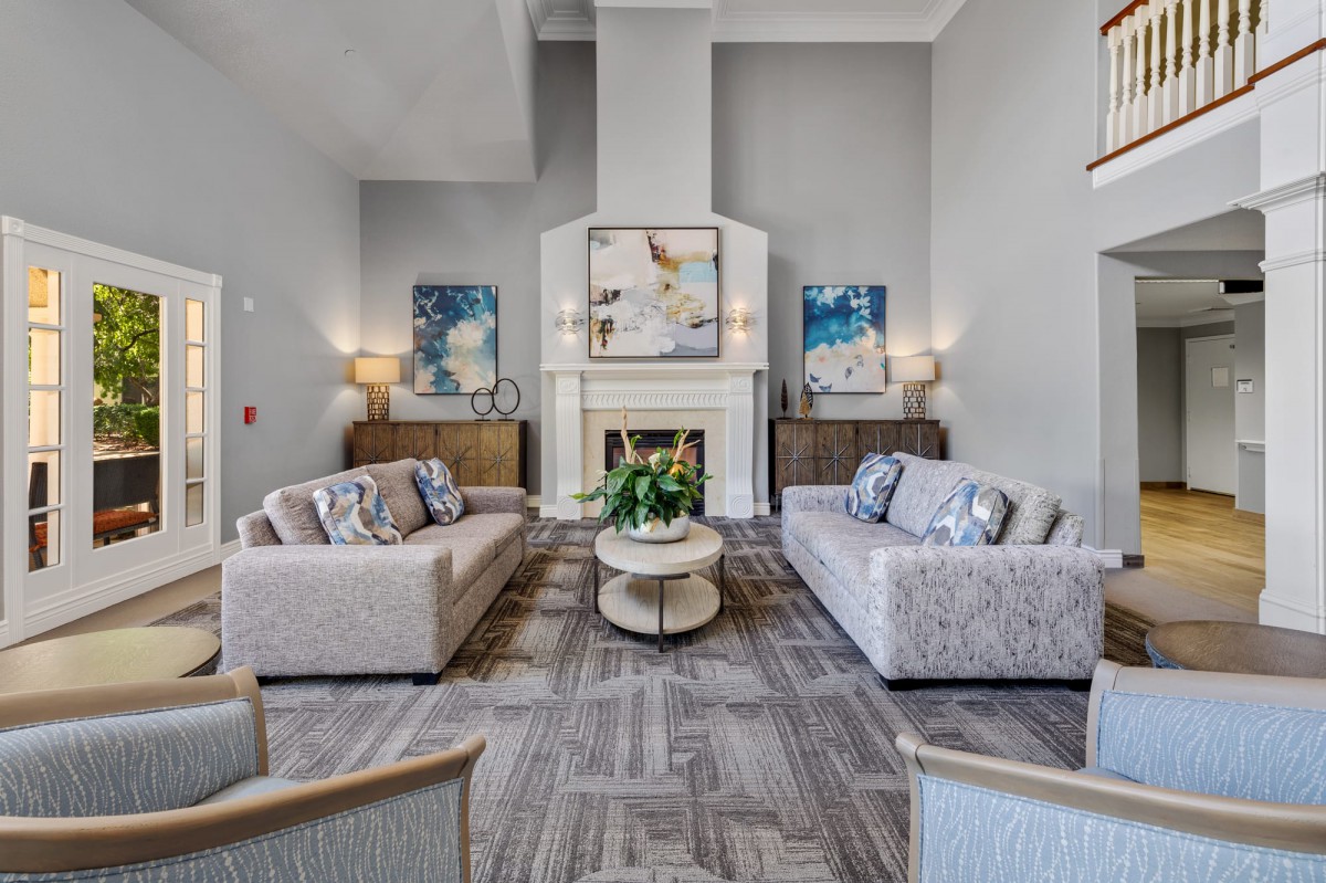 A modern living room with two sofas facing each other, a central coffee table, and a fireplace adorned with decorative art.