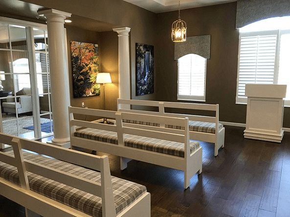 A well-lit room with white benches, decorative columns, and artwork on the walls.
