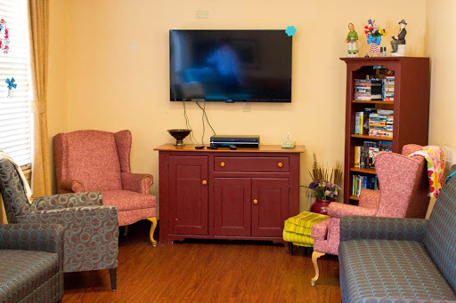 A cozy living room featuring a television mounted on the wall, a walnut cabinet, and comfortable armchairs.