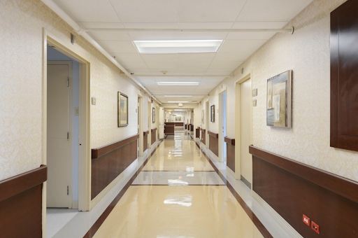 A well-lit hospital hallway featuring smooth flooring and framed artworks on the walls.
