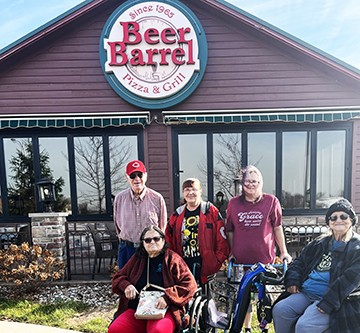 A cheerful group gathered outside the Beer Barrel restaurant, enjoying a sunny day.