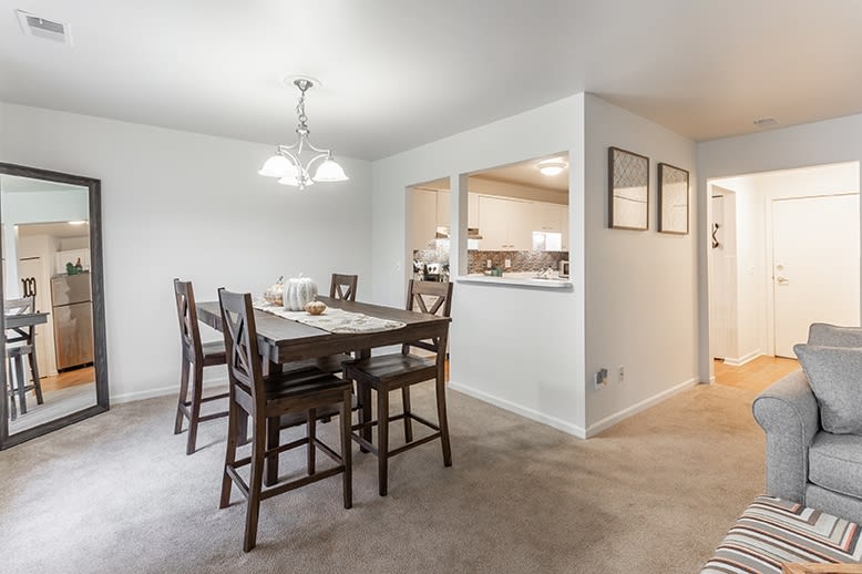 A modern dining area with a wooden table and high chairs, featuring an open layout.
