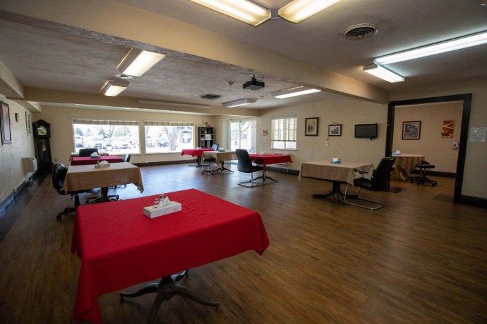 A spacious dining area with tables covered in red tablecloths and large windows providing natural light.