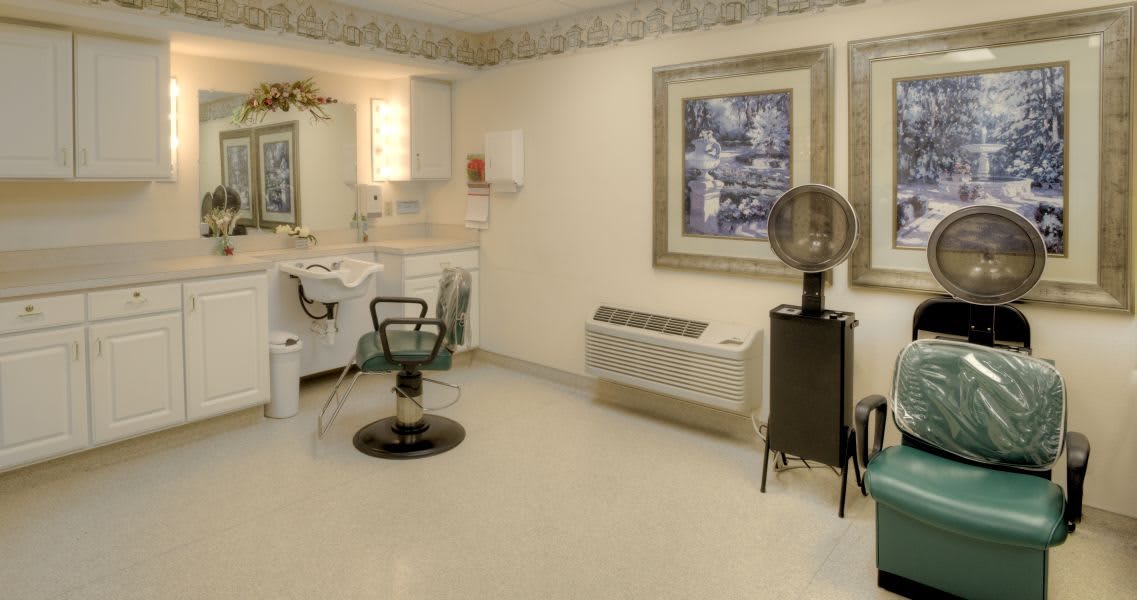 An empty hair salon with a styling chair and hair dryer set against a neatly decorated interior.