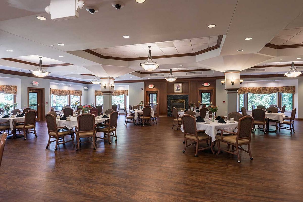 An elegant and spacious dining room with neatly arranged tables and chairs, adorned with warm lighting.
