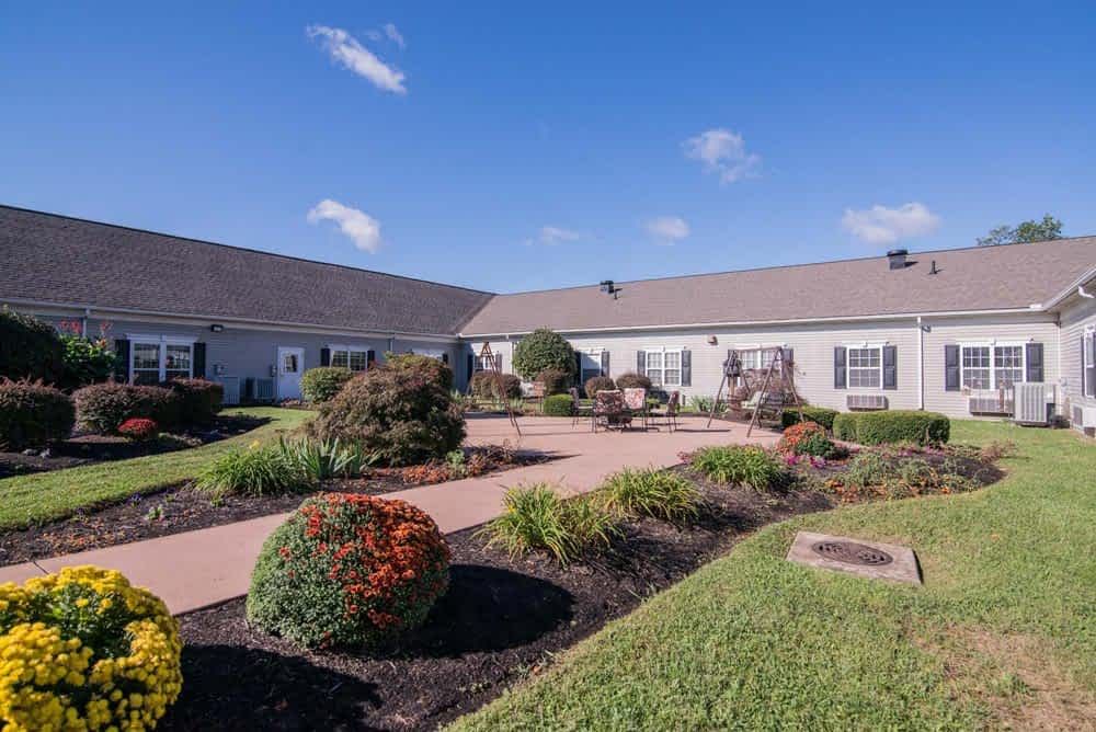 A well-maintained garden with a pathway leading to a residential building under a clear blue sky.