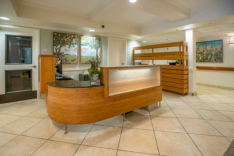 A modern office reception area featuring a curved wooden desk and tile flooring.