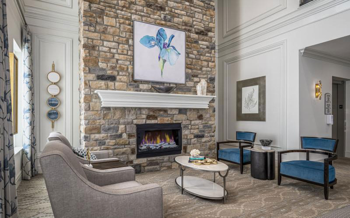 A modern living room featuring a stone wall with a fireplace, complemented by contemporary furniture and artwork.