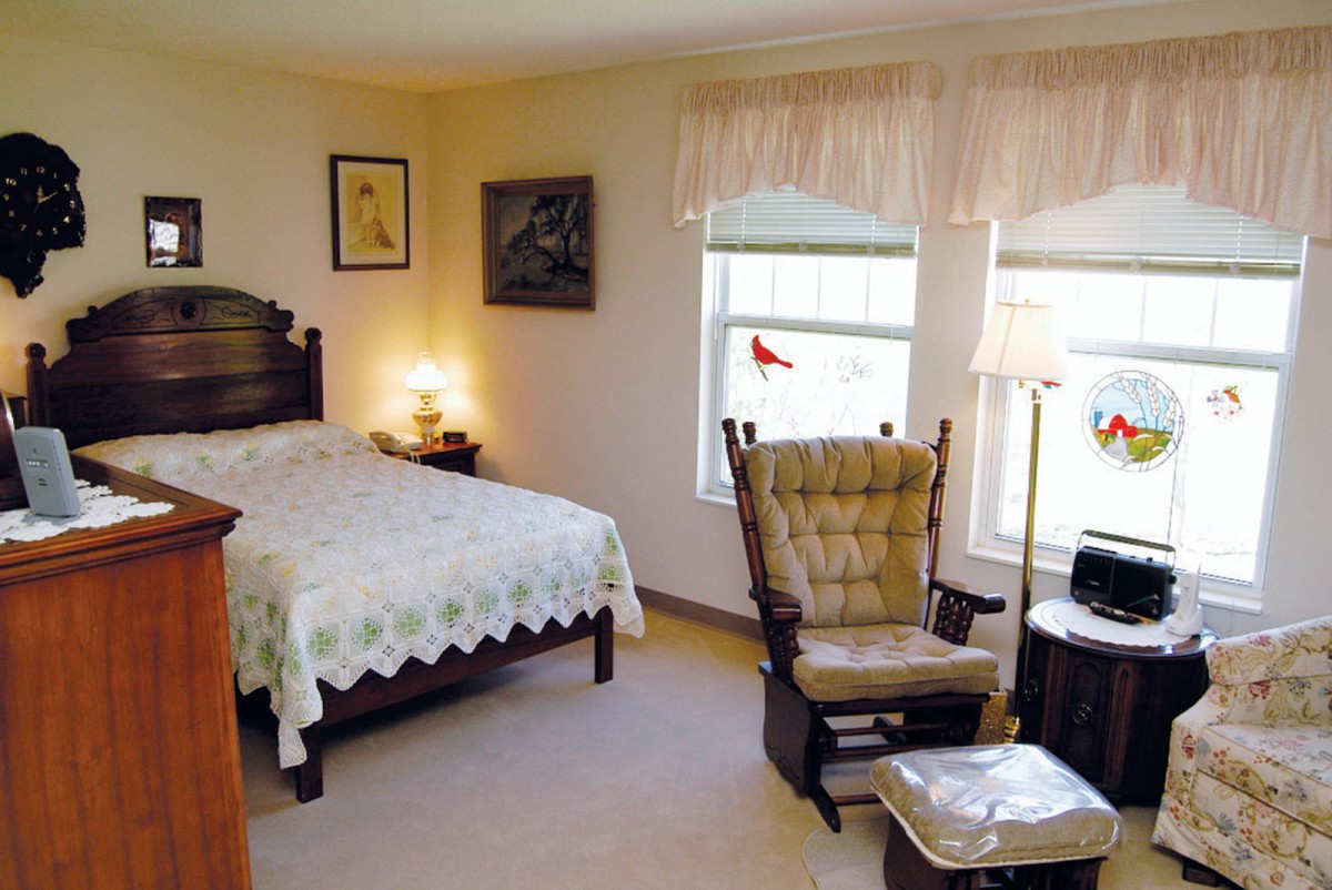 Cozy bedroom with a bed, rocking chair, and large windows.