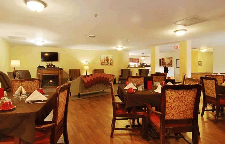 A cozy dining room with several tables and chairs, warm lighting, and tasteful decor.