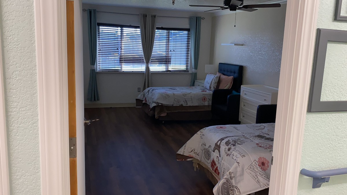 A spacious bedroom with two beds, wooden flooring, and large windows.