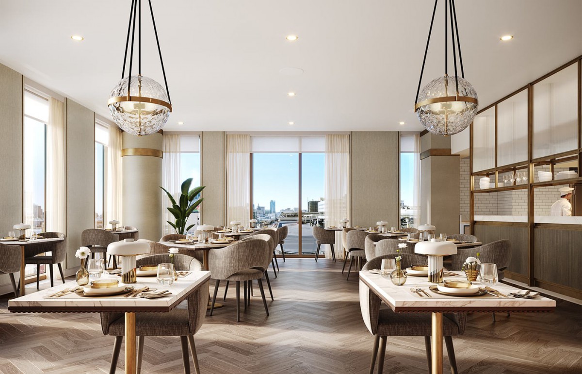 A modern dining area with elegant chandeliers and well-arranged tables, flooded with natural light from large windows.