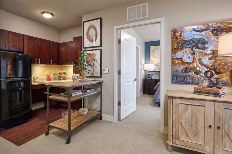 A cozy apartment interior showcasing a kitchen area with rich wooden cabinets and a hallway leading to a bedroom.
