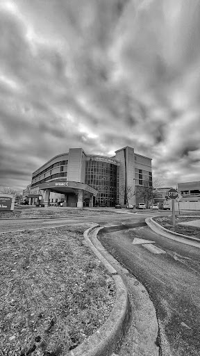 A modern architectural structure captured in black and white under a dramatic cloudy sky.