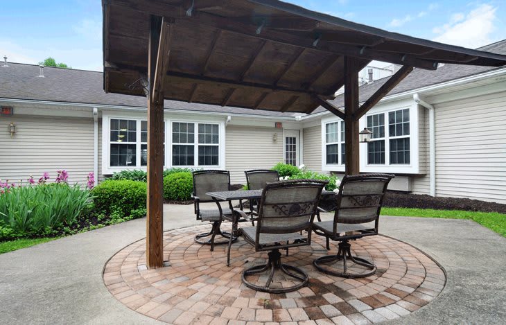 A cozy outdoor patio with a table and chairs under a gazebo.