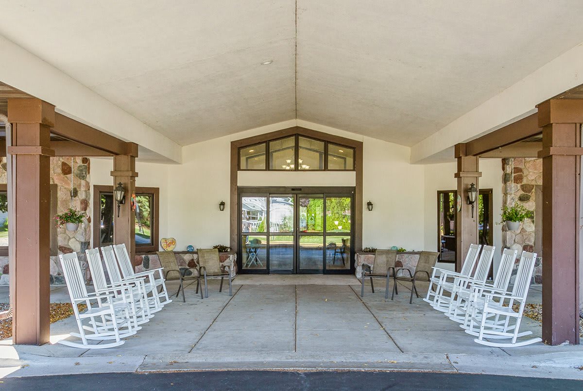 The entrance of a building features rocking chairs on a spacious porch.