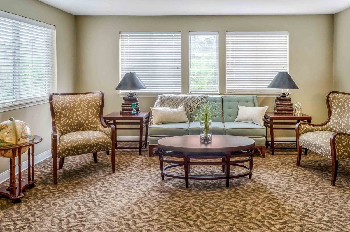 A cozy living room with a sofa, armchairs, and a coffee table surrounded by warm lighting.