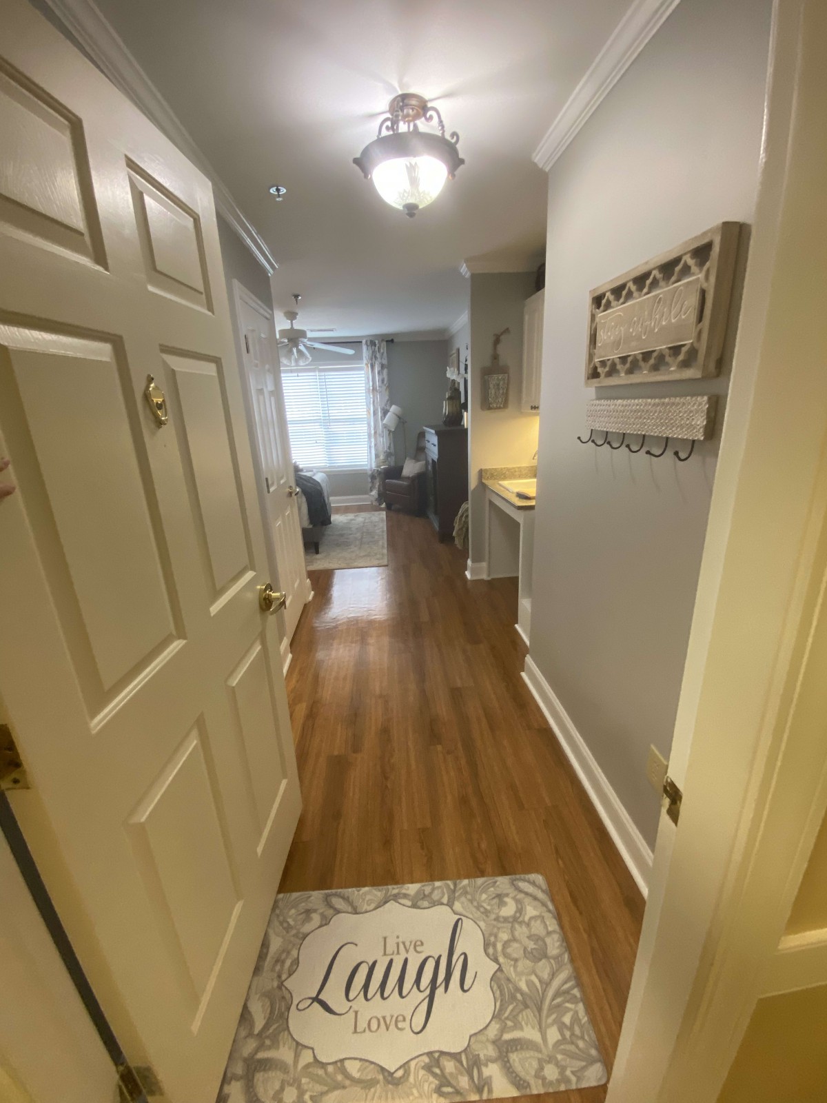 A view of a modern apartment hallway with wooden flooring leading to a bright living space.