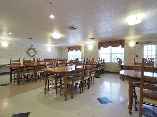 A spacious and well-lit dining room featuring wooden tables and chairs, designed for communal dining.