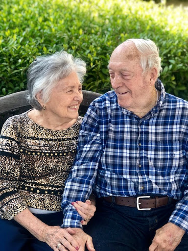 An elderly couple enjoys a joyful moment together outdoors.