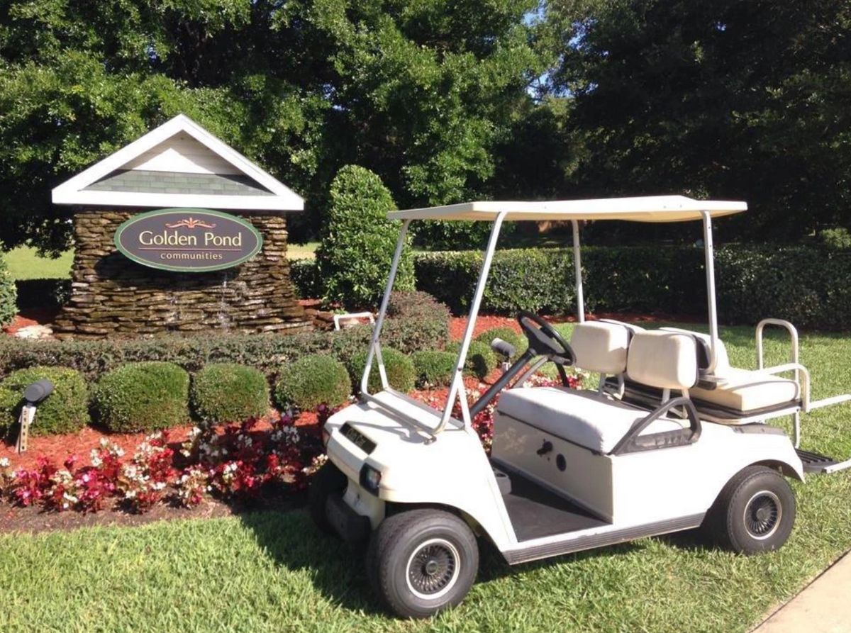 A golf cart parked in front of a landscaped area with a sign reading 'Garden Park'.