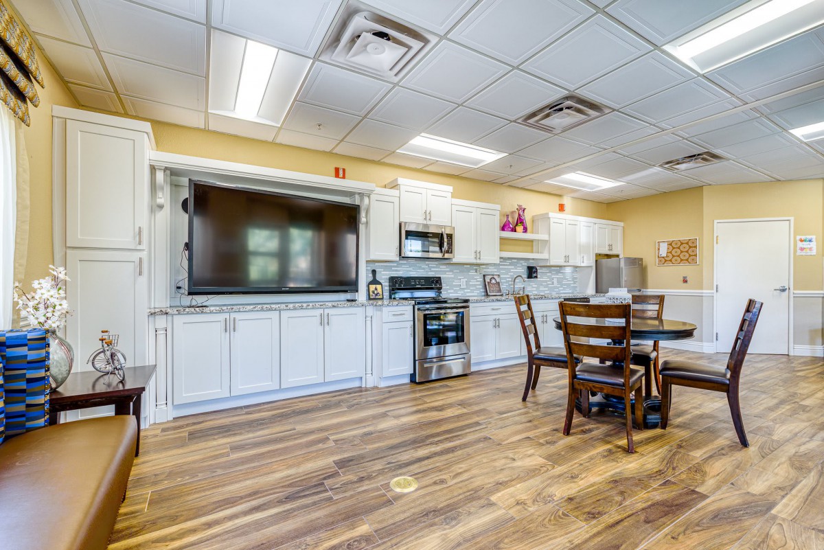 A modern kitchen with white cabinetry, a dining table, and various appliances.