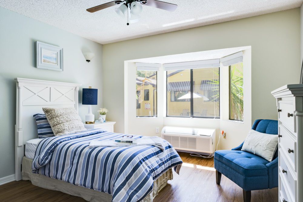 A bright and modern bedroom with a striped bedspread and large window.