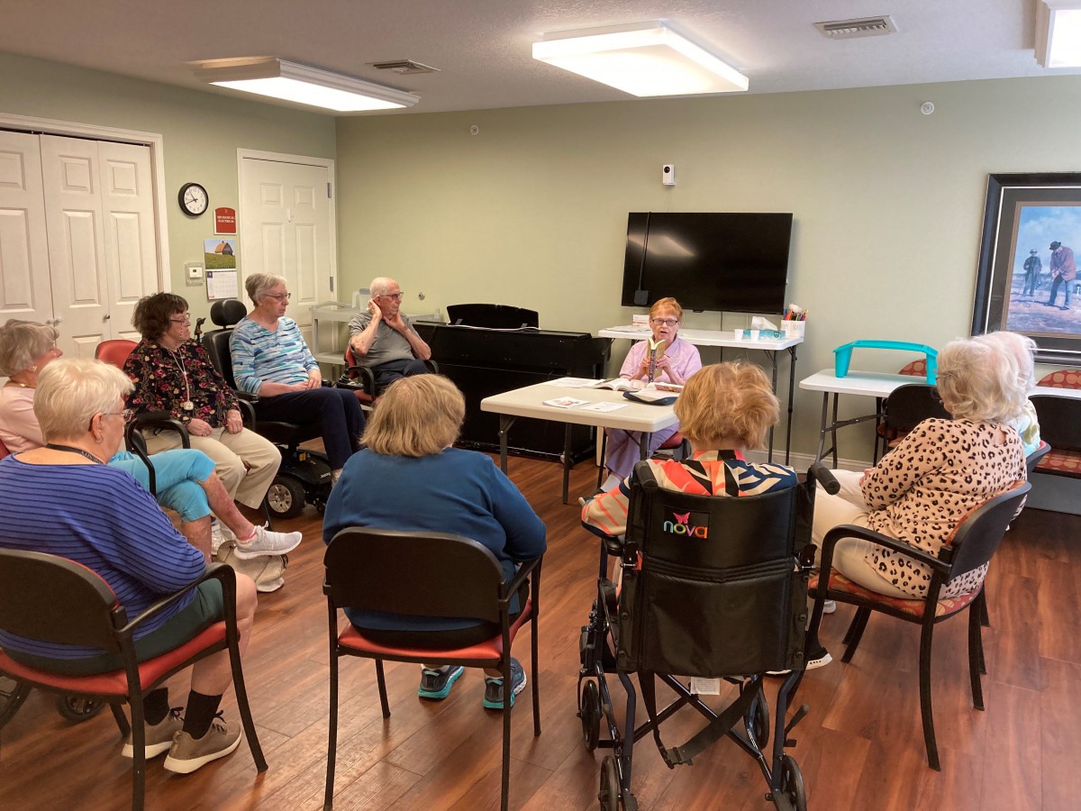 A group of seniors engaged in a community meeting inside a room.