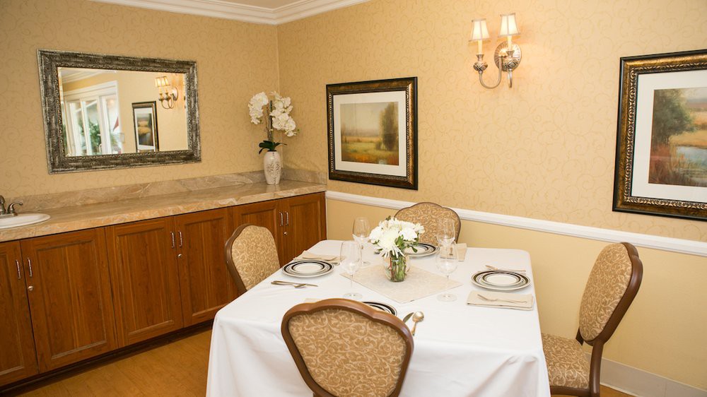 A neatly set dining table with elegant decor, featuring flowers and artwork on the wall.