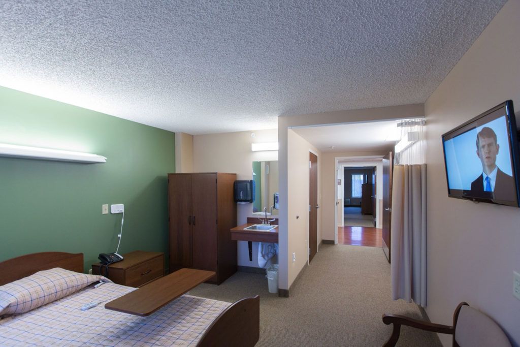 A modern and comfortable hotel room interior with a bed, wardrobe, and a small desk area.