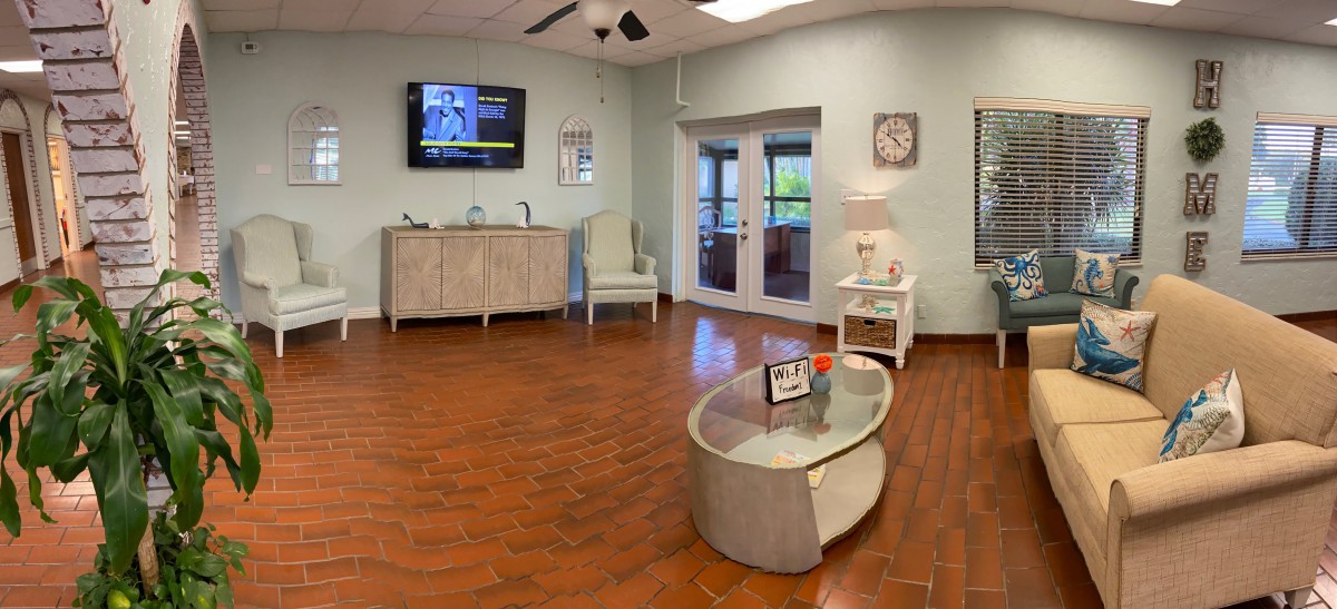A comfortable waiting room with a television, clock, and seating area on a wooden floor.