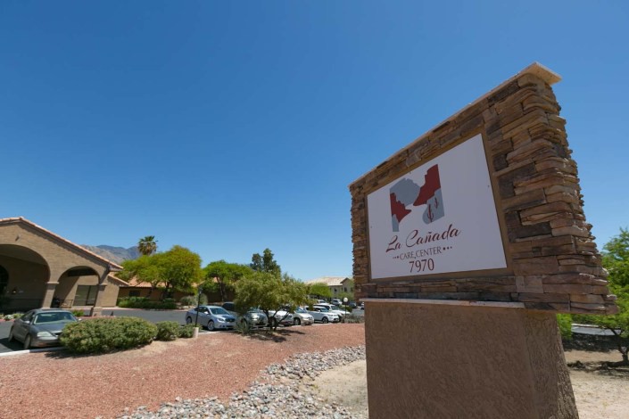An outdoor view of a building with a sign and parking lot on a sunny day.