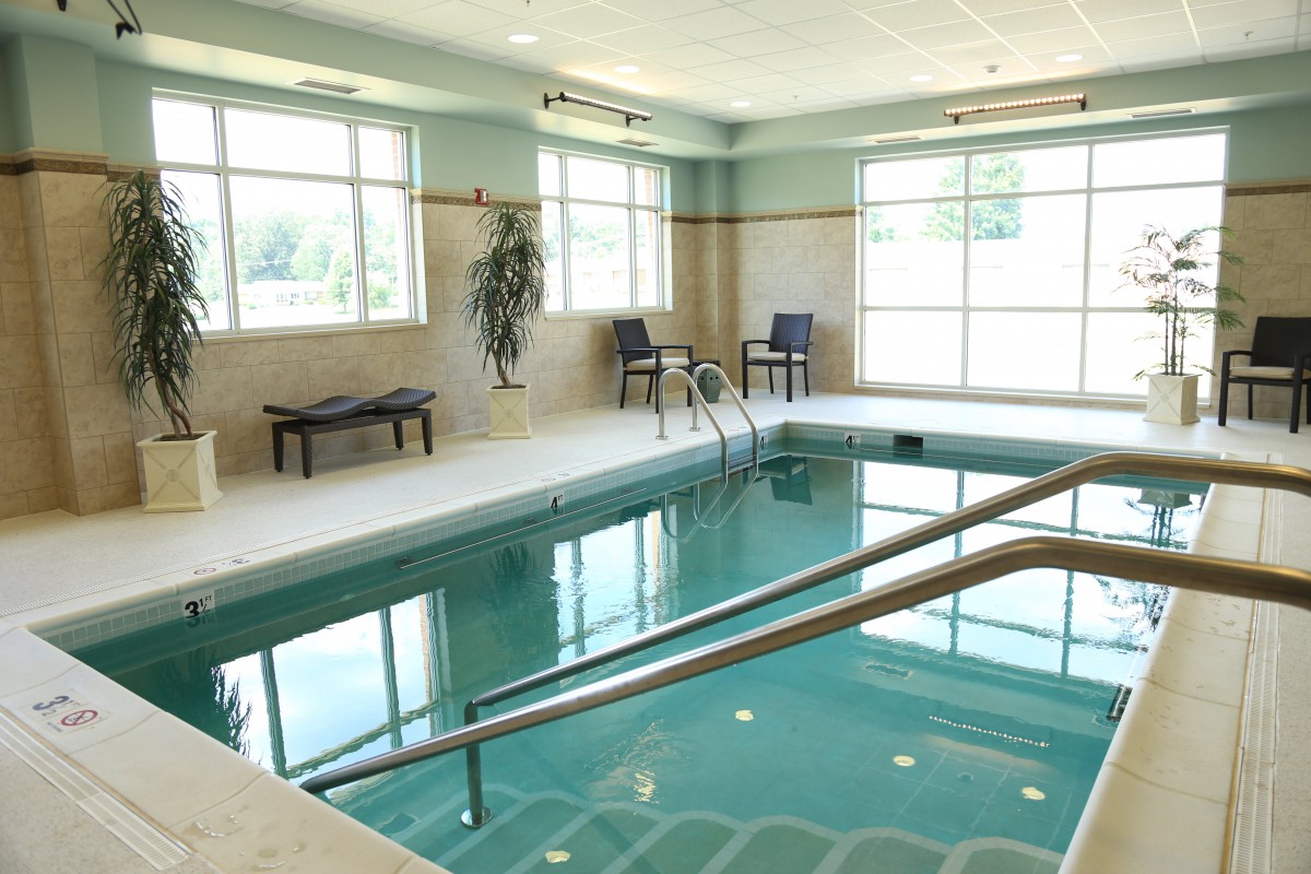 A serene indoor swimming pool surrounded by chairs and windows.