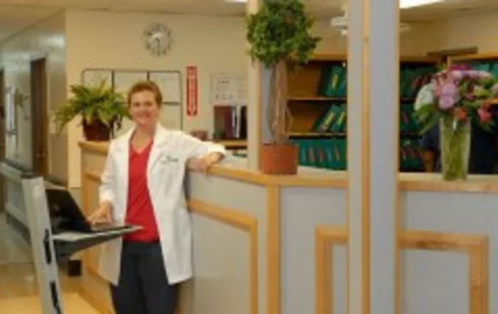 A medical professional stands in a hospital or clinic setting.