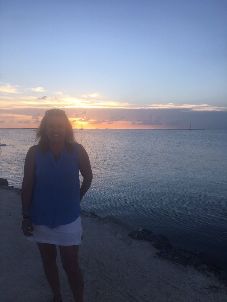 Person standing by the ocean at sunset.