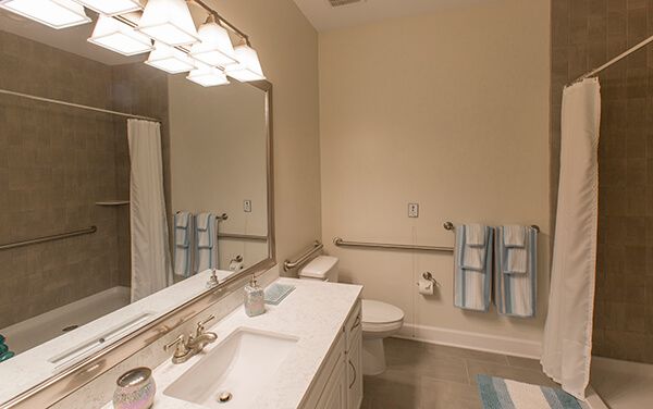 A well-lit bathroom featuring a sink, mirror, and neatly arranged towels.