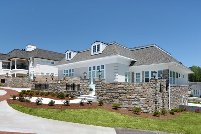 A modern residential house with stone walls and well-maintained landscaping.