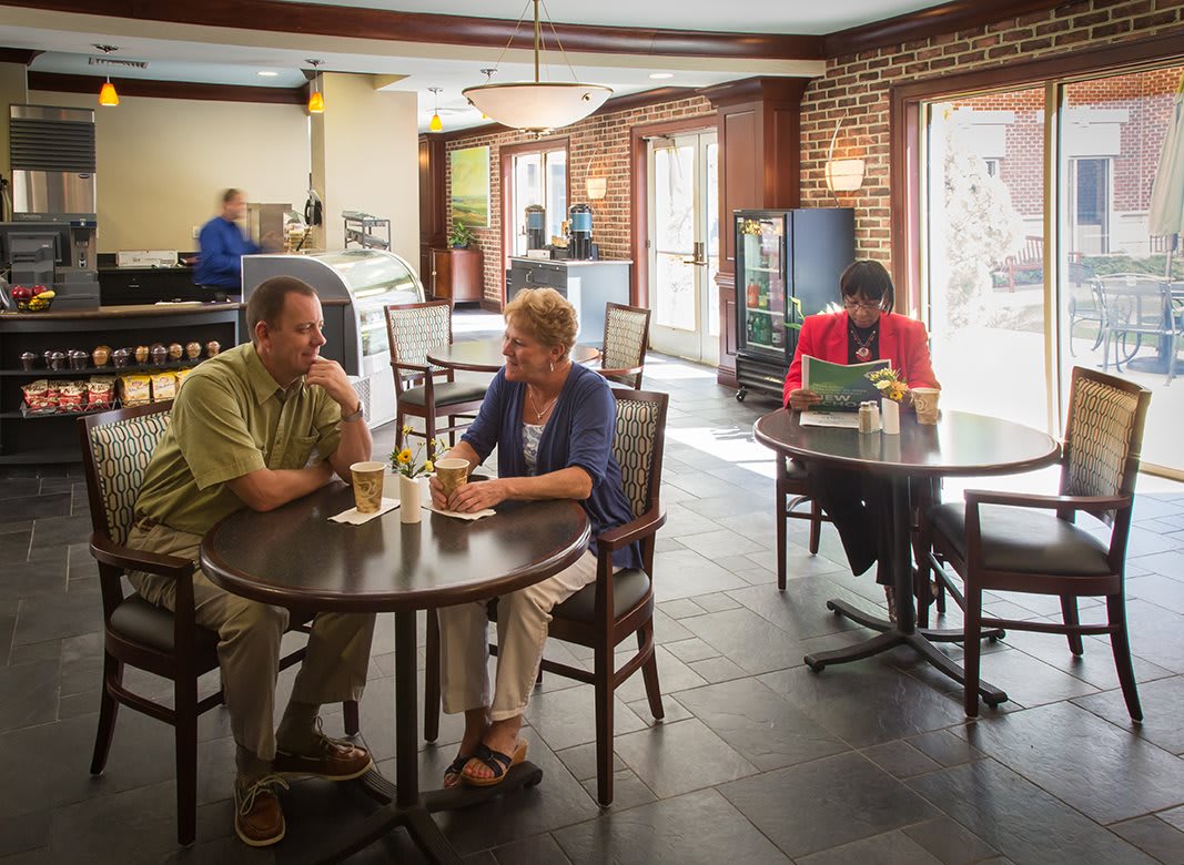 People in a cafe having conversations and using a laptop.