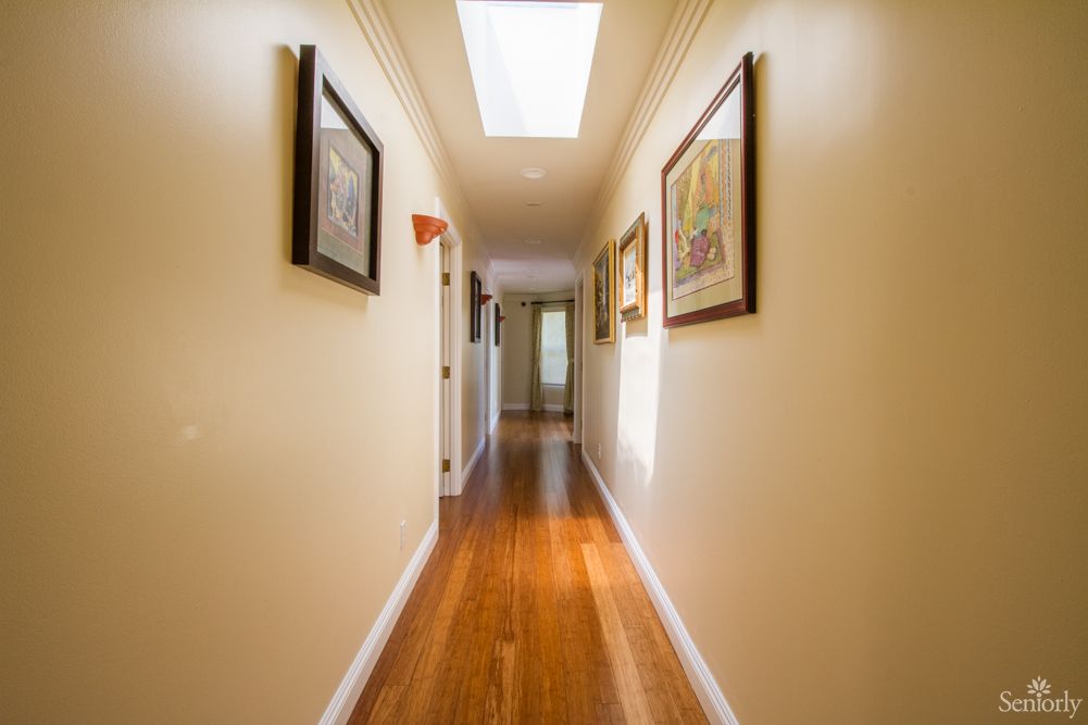 A well-lit hallway with wooden floors and artwork on the walls.