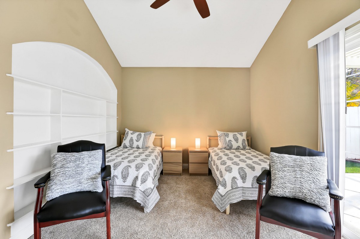 A cozy bedroom with twin beds, bedside tables with lamps, and two chairs.
