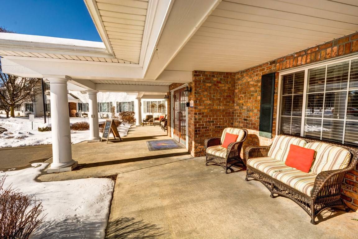 A spacious and inviting patio with comfortable seating under a covered porch on a sunny day.